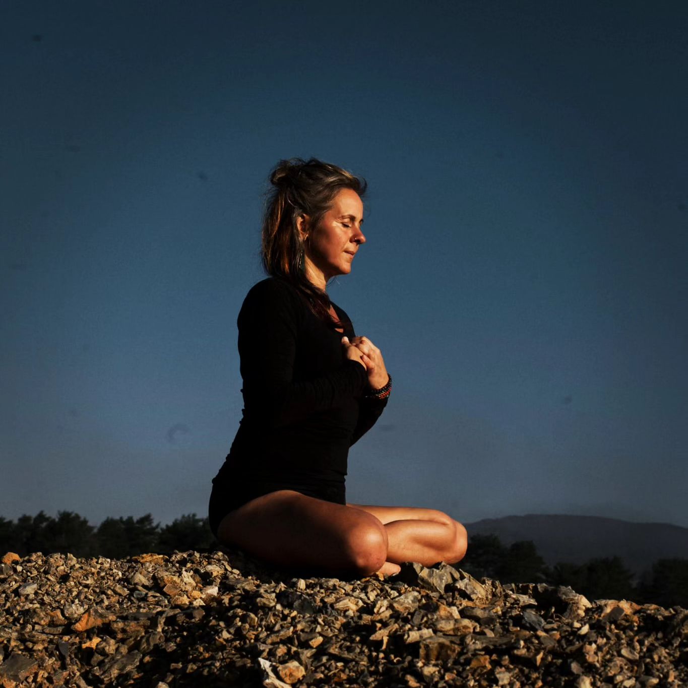Sandy Weigt in stiller Meditation auf einem Hügel in der Abenddämmerung